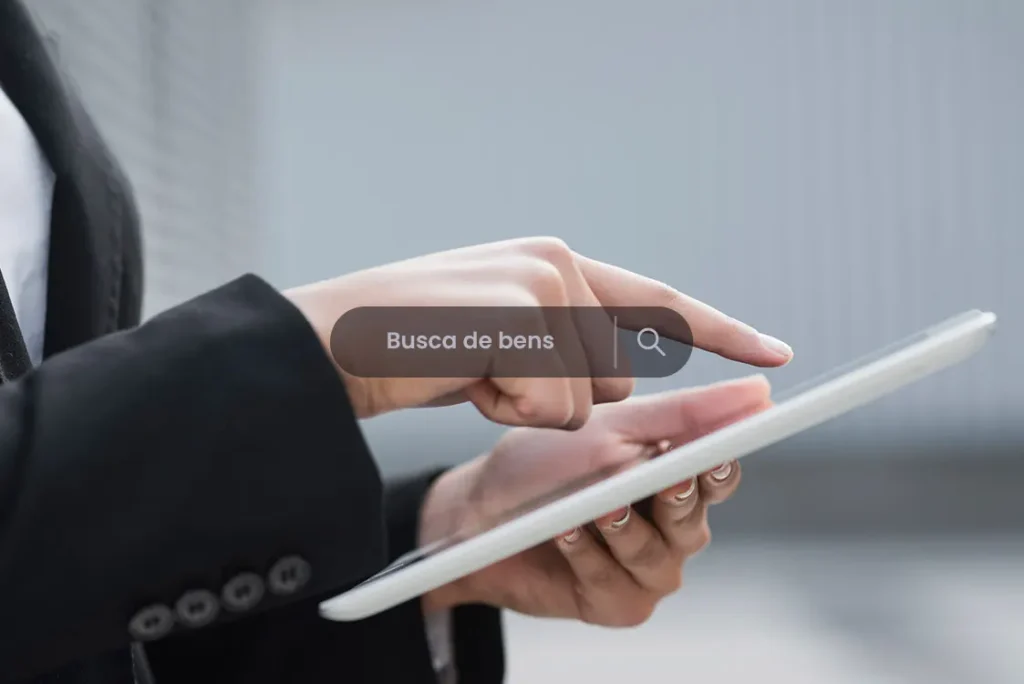 Mãos femininas manuseiam um tablet de bordas brancas em busca dos bens do devedor